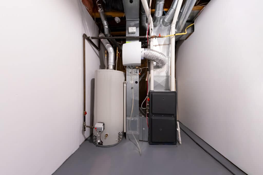 A clean and organized utility area featuring a hot water heater, a furnace, and ventilation ducts. The walls are painted white, and the floor is concrete, creating a functional space for heating and plumbing equipment.