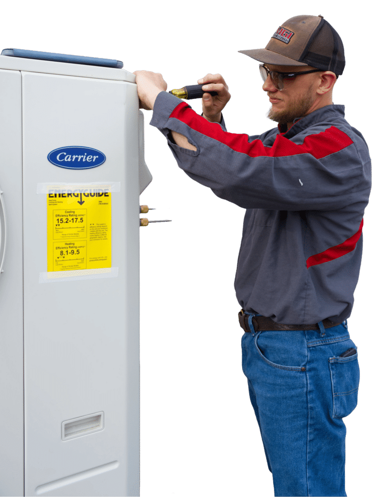 A technician wearing a gray and red shirt and glasses is using a screwdriver to work on a Carrier brand appliance. A yellow EnergyGuide label is visible on the appliance's side, providing efficiency information.